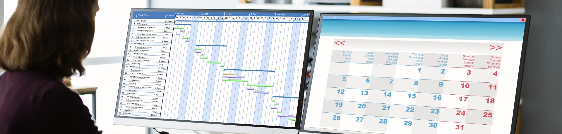 Person using dual monitors displaying a Gantt chart and calendar, possibly planning for a grant writing project timeline.